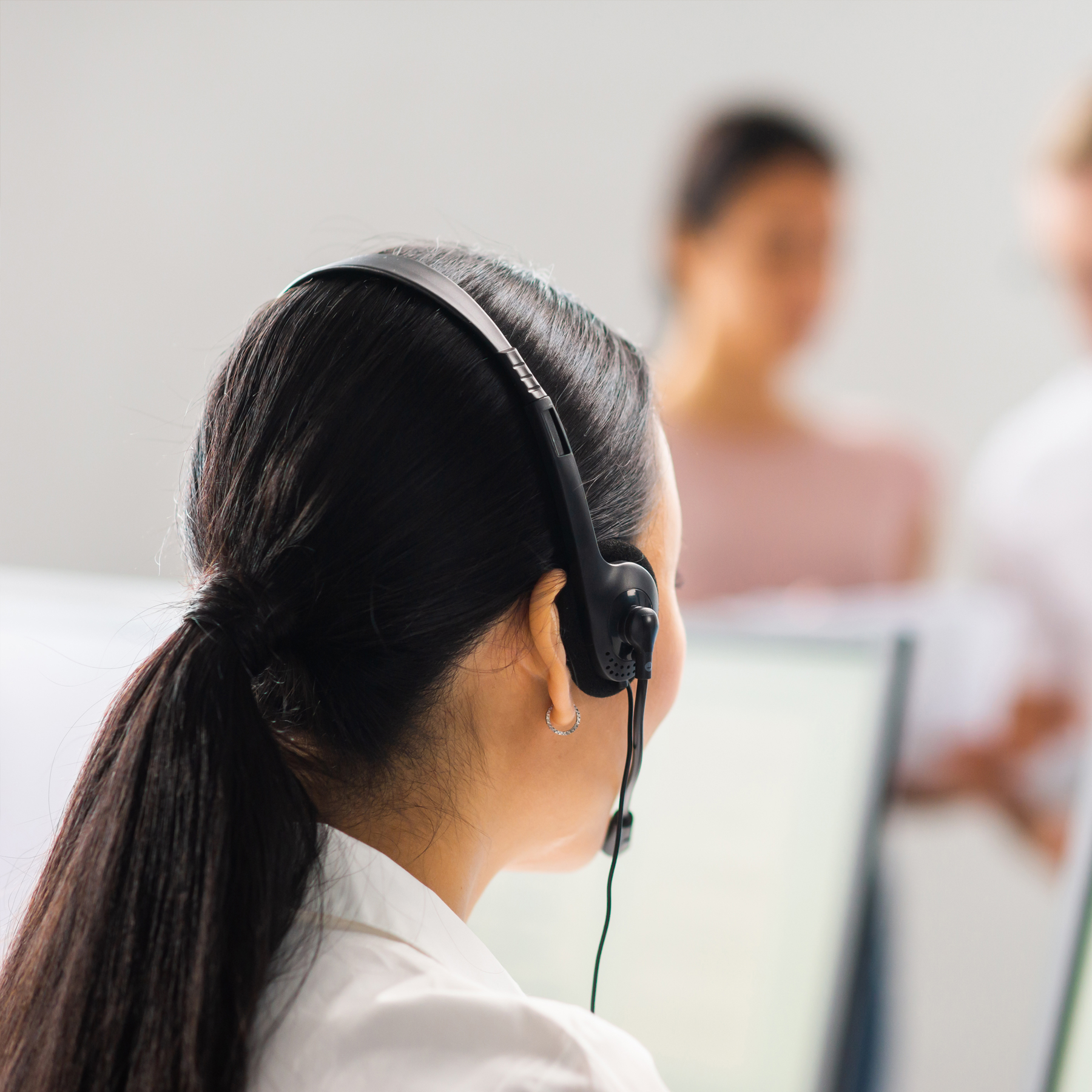 Dunkelhaarige Frau mit Headset, die im Kundenservice arbeitet