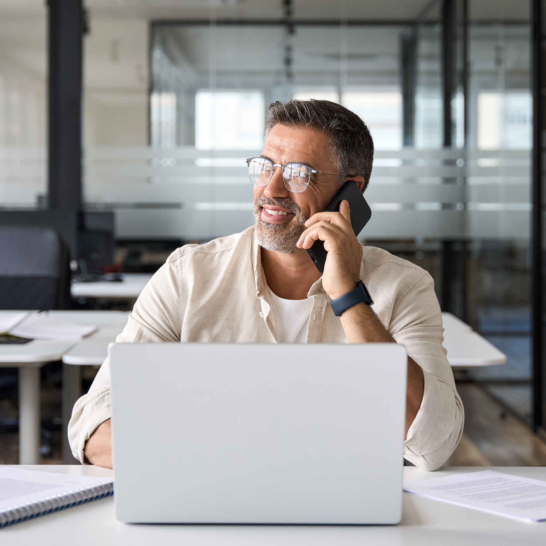 Mann mit Brille vor einem Laptop telefoniert